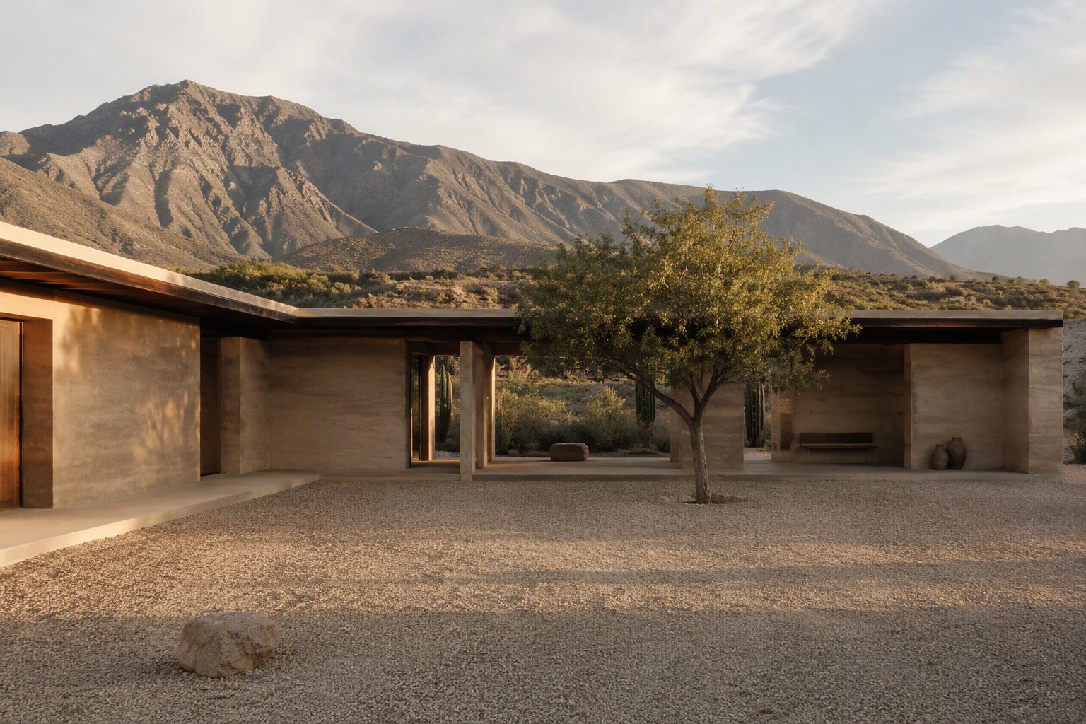 Casa del Cauce — patio con muros de tapia y montañas andinas